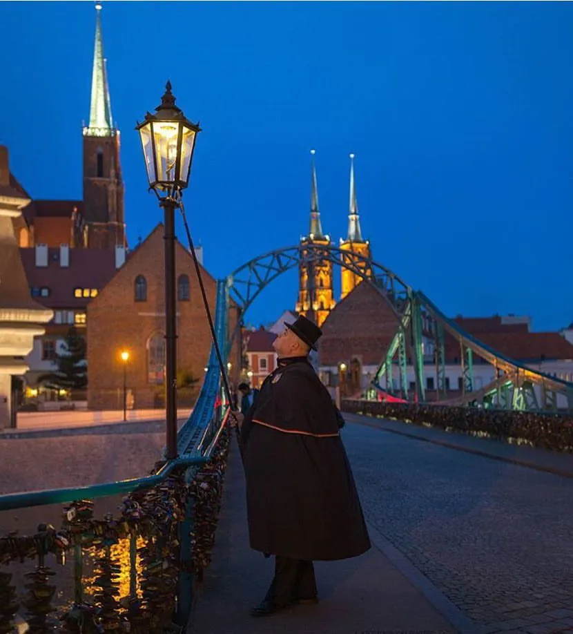 Latarnik zapalający latarnie gazowe na moście Tumskim